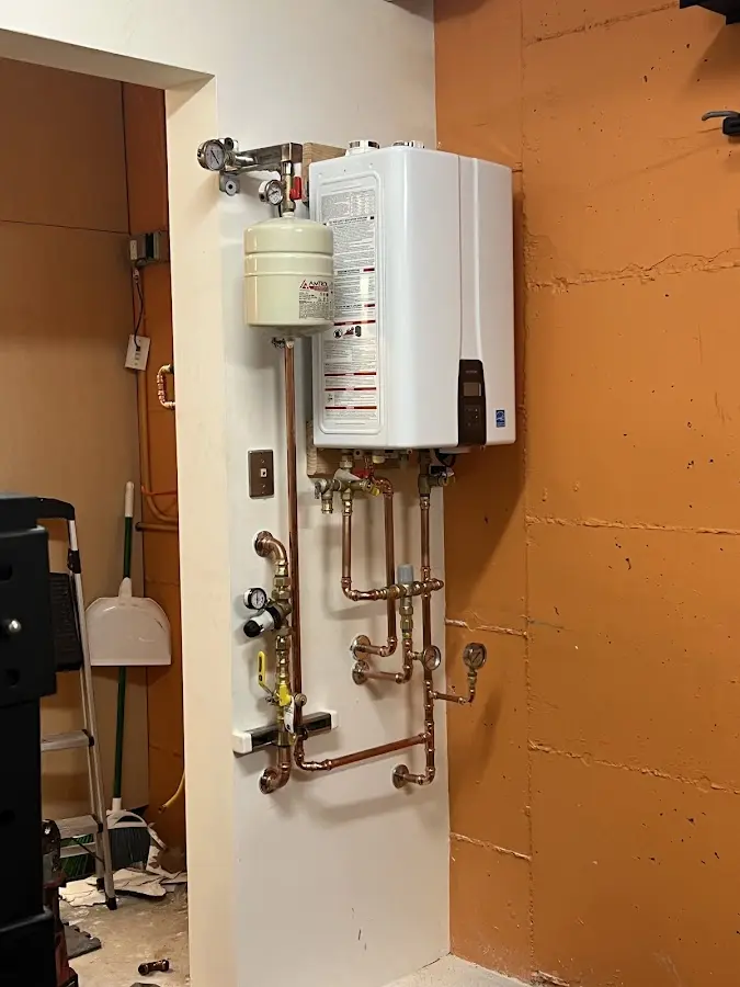 Plumbing technician inspecting water heater connections in Fife